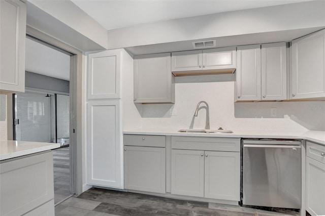 kitchen with stainless steel dishwasher, sink, light hardwood / wood-style flooring, and white cabinets