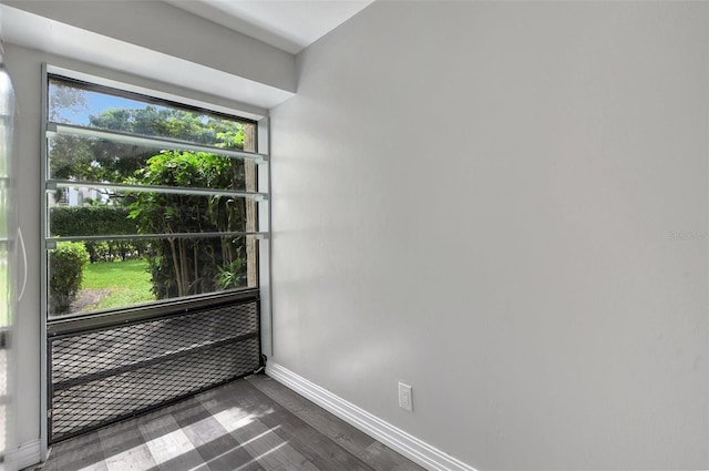 unfurnished room featuring baseboards and dark wood finished floors