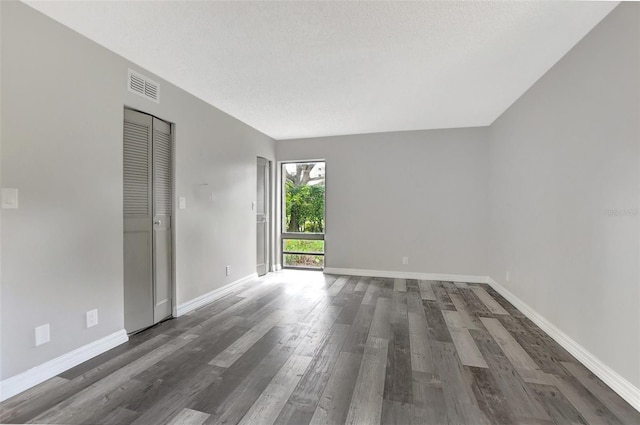 spare room featuring a textured ceiling and dark hardwood / wood-style flooring