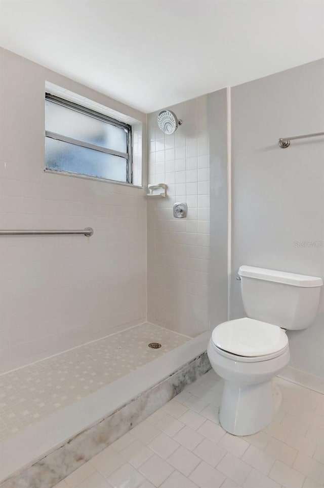 bathroom with tiled shower, toilet, and tile patterned floors