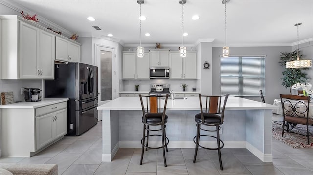 kitchen featuring appliances with stainless steel finishes, white cabinetry, a kitchen island with sink, and decorative light fixtures