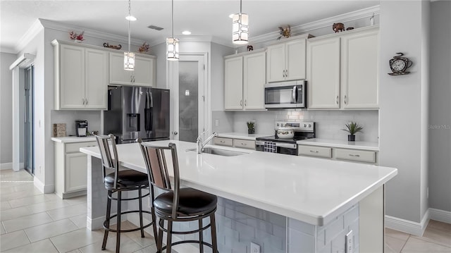 kitchen featuring sink, an island with sink, hanging light fixtures, stainless steel appliances, and a breakfast bar