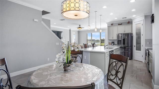 kitchen with a center island with sink, appliances with stainless steel finishes, a breakfast bar, white cabinetry, and crown molding