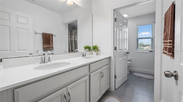 bathroom with toilet, vanity, and tile patterned floors