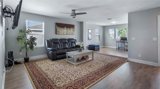 living room featuring ceiling fan, wood-type flooring, and a textured ceiling