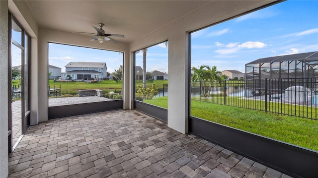 unfurnished sunroom featuring a water view and ceiling fan