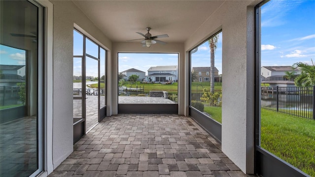 unfurnished sunroom featuring a water view and ceiling fan