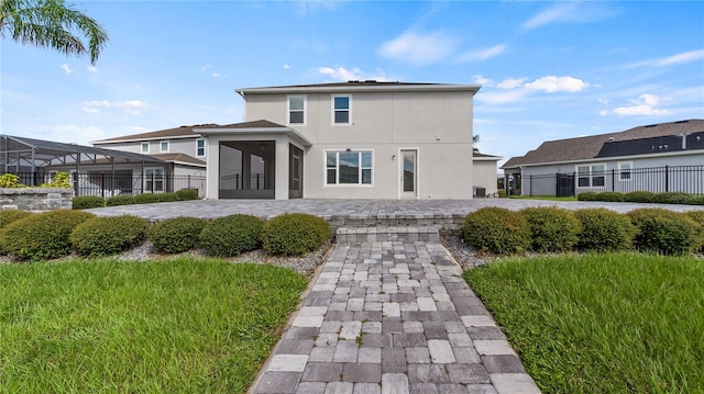 rear view of house featuring a patio and glass enclosure