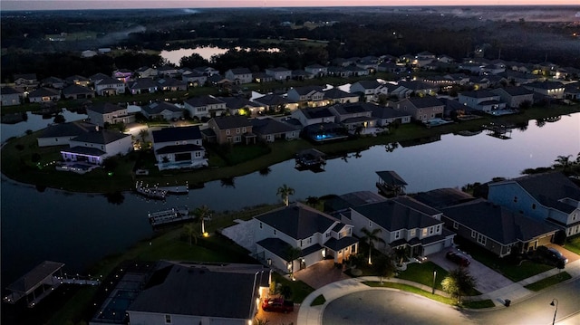 aerial view at dusk featuring a water view