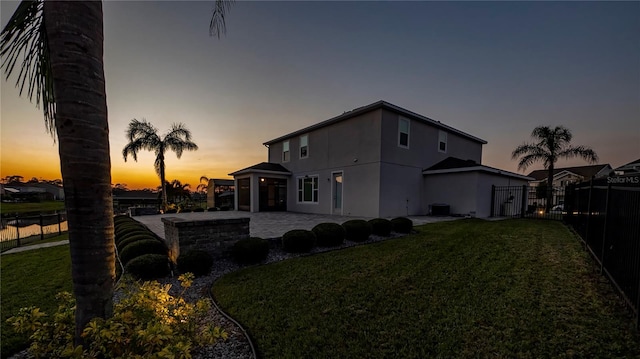 property exterior at dusk featuring a patio area, a yard, and cooling unit