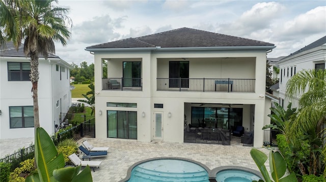 back of property featuring a balcony, a swimming pool with hot tub, and a patio area