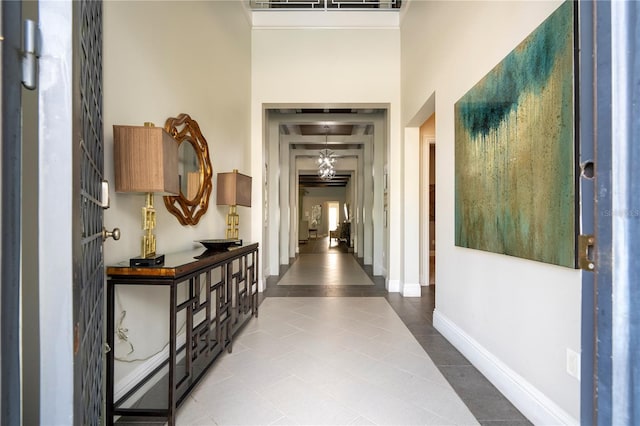 corridor with an inviting chandelier, a high ceiling, and light tile patterned flooring