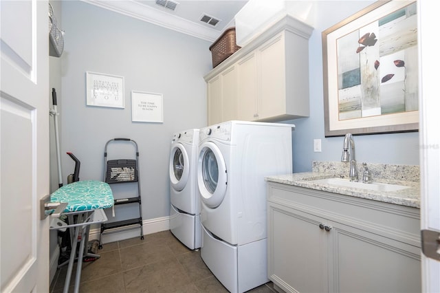 laundry area with crown molding, dark tile patterned floors, cabinets, sink, and washer and dryer