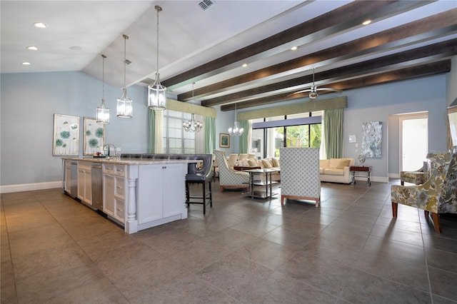 kitchen featuring pendant lighting, light stone counters, a breakfast bar area, white cabinets, and a center island with sink