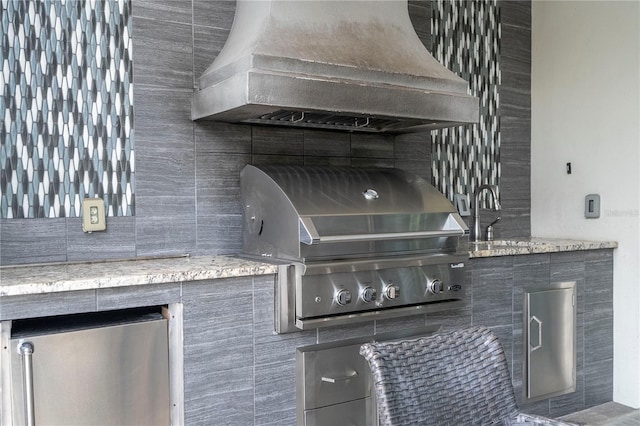 exterior details featuring wall chimney exhaust hood, decorative backsplash, sink, and stainless steel fridge