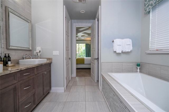 bathroom featuring a relaxing tiled tub, vanity, and tile patterned floors