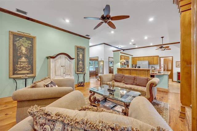 living room with ceiling fan, light wood-type flooring, sink, and crown molding