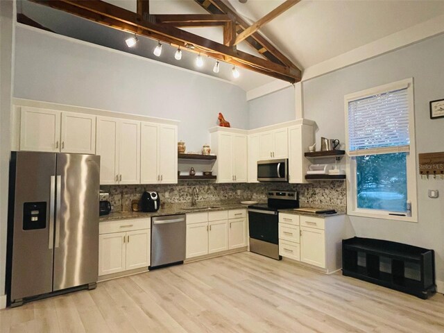 kitchen featuring appliances with stainless steel finishes, decorative backsplash, beam ceiling, white cabinets, and sink