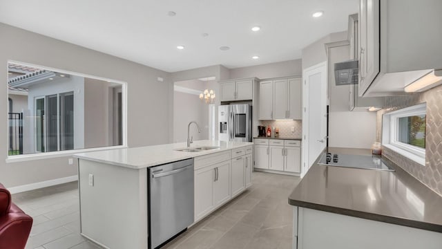 kitchen with an island with sink, sink, tasteful backsplash, white cabinetry, and stainless steel appliances