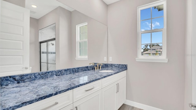 bathroom featuring wood-type flooring, an enclosed shower, and vanity