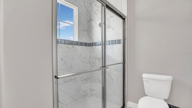 bathroom featuring toilet and a shower with shower door