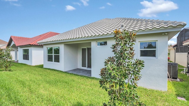 rear view of property with a lawn and central air condition unit