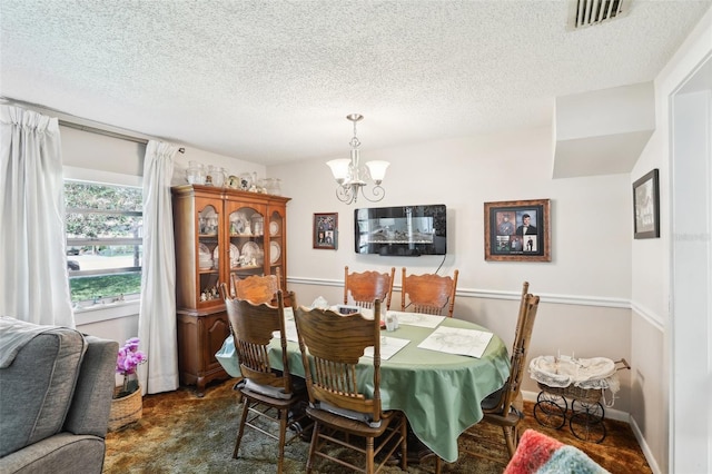 dining space with an inviting chandelier and a textured ceiling