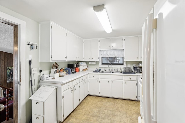 kitchen featuring white cabinetry, white refrigerator, and sink