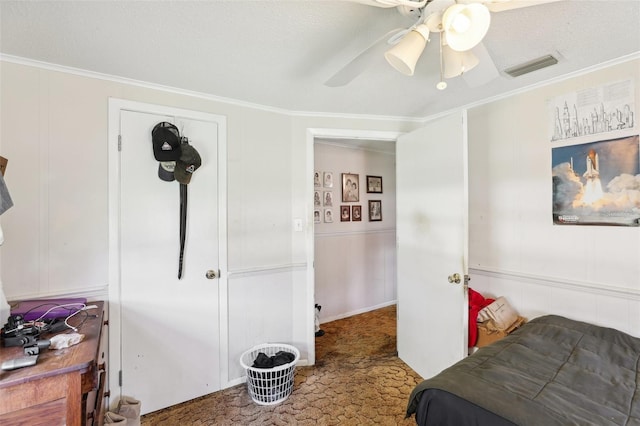 carpeted bedroom with a textured ceiling, ceiling fan, and crown molding