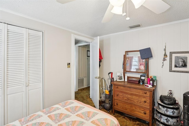 bedroom featuring ornamental molding, ceiling fan, dark carpet, and a closet