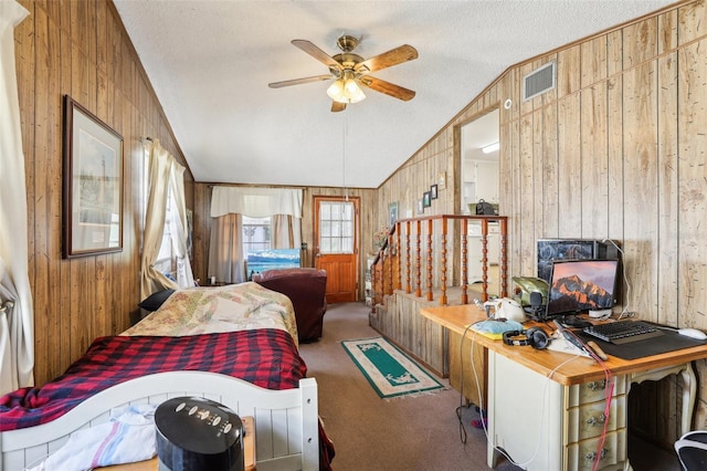 carpeted bedroom featuring a textured ceiling, wooden walls, vaulted ceiling, and ceiling fan