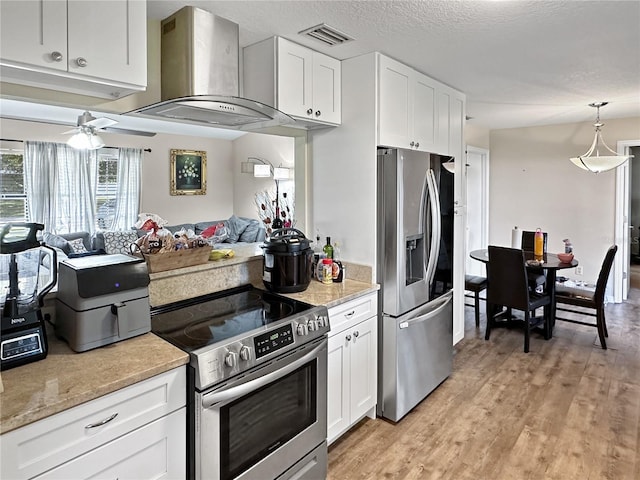 kitchen featuring light hardwood / wood-style floors, white cabinetry, stainless steel appliances, ceiling fan, and wall chimney range hood