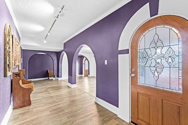 entryway featuring light hardwood / wood-style flooring, a textured ceiling, ornamental molding, and rail lighting