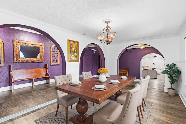 dining area with hardwood / wood-style flooring, ceiling fan with notable chandelier, a textured ceiling, and crown molding