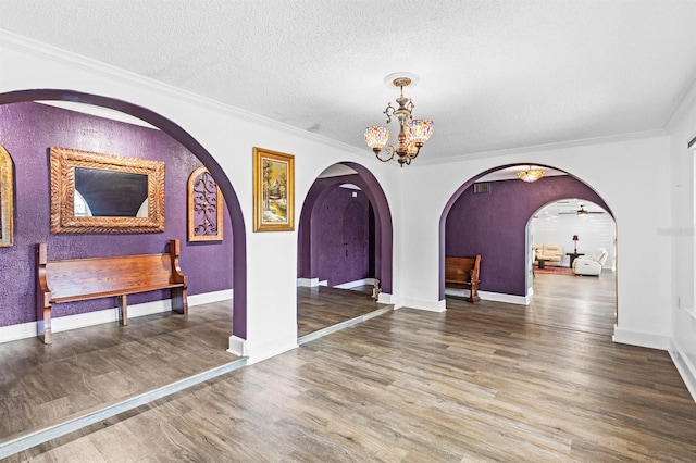 interior space with ornamental molding, ceiling fan with notable chandelier, a textured ceiling, and hardwood / wood-style flooring