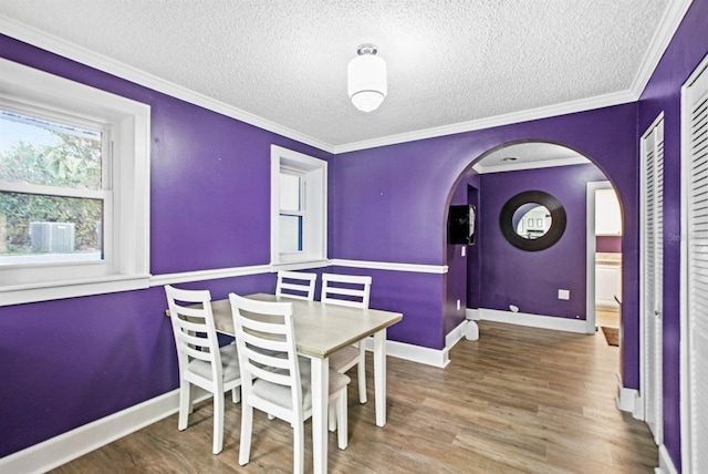 dining area with ornamental molding, a textured ceiling, and hardwood / wood-style flooring