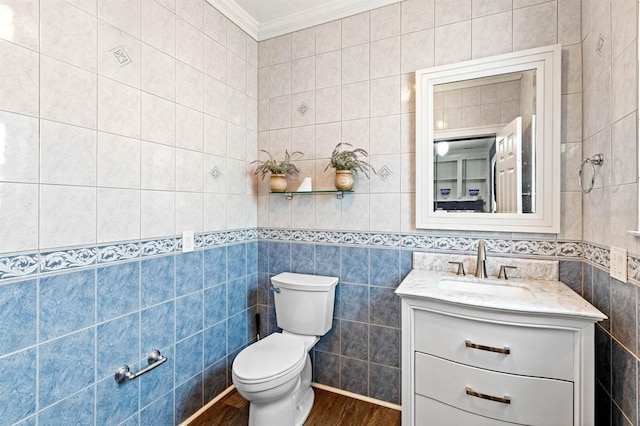 bathroom featuring wood-type flooring, toilet, tile walls, vanity, and crown molding