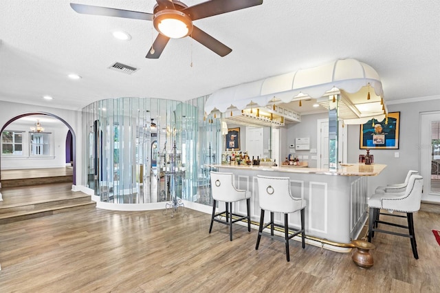 bar with ceiling fan, hardwood / wood-style floors, ornamental molding, and a textured ceiling