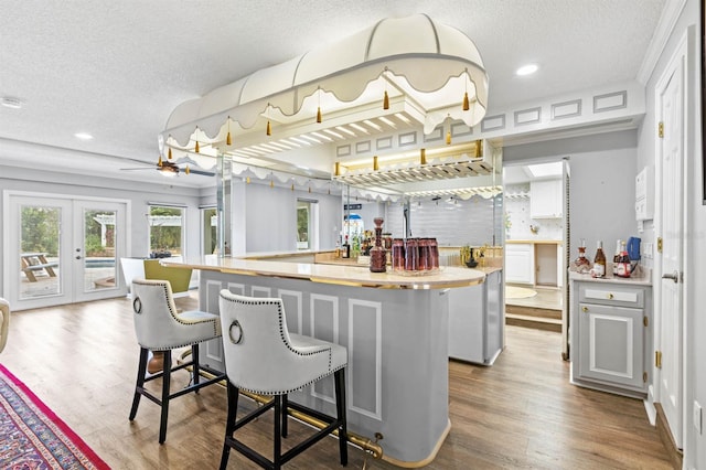 kitchen with hardwood / wood-style flooring, a textured ceiling, a breakfast bar, and french doors