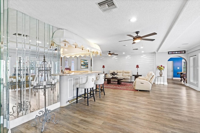 interior space with a textured ceiling, hardwood / wood-style floors, and a breakfast bar area