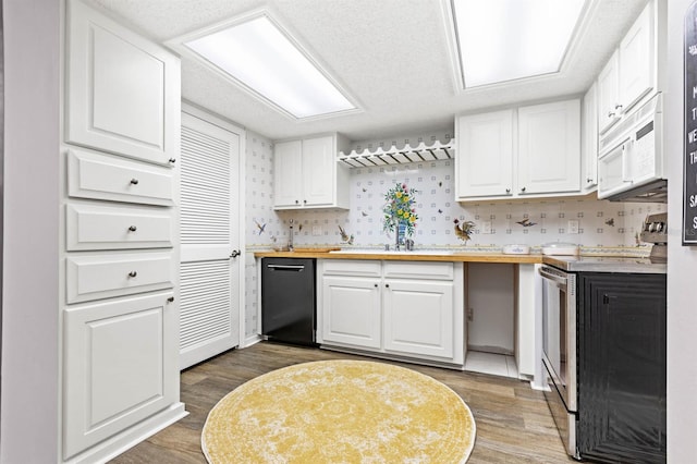 kitchen with dark wood-type flooring, black dishwasher, stainless steel range with electric stovetop, butcher block countertops, and white cabinetry