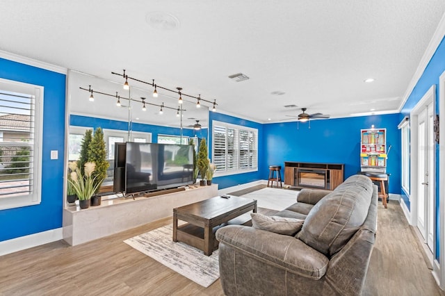 living room with ceiling fan, a high end fireplace, light hardwood / wood-style floors, and crown molding