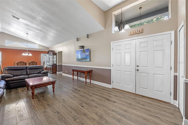 entryway featuring vaulted ceiling, a chandelier, hardwood / wood-style floors, and a textured ceiling