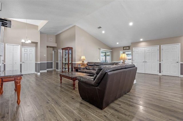 living room with an inviting chandelier, dark hardwood / wood-style flooring, and high vaulted ceiling