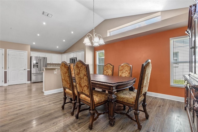 dining space with an inviting chandelier, high vaulted ceiling, and light hardwood / wood-style floors