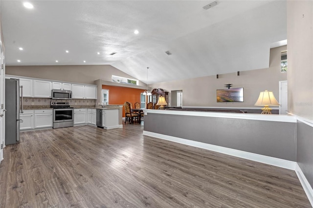 kitchen with hardwood / wood-style floors, white cabinets, decorative backsplash, kitchen peninsula, and stainless steel appliances