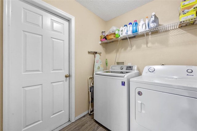 laundry area featuring hardwood / wood-style floors, washing machine and dryer, and a textured ceiling