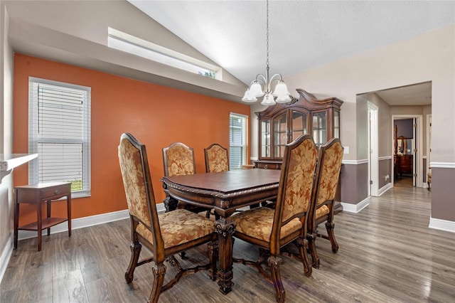 dining space featuring a notable chandelier, vaulted ceiling, dark hardwood / wood-style floors, and a textured ceiling