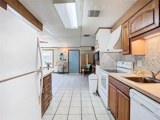 kitchen with decorative backsplash, light tile patterned flooring, white appliances, exhaust hood, and sink