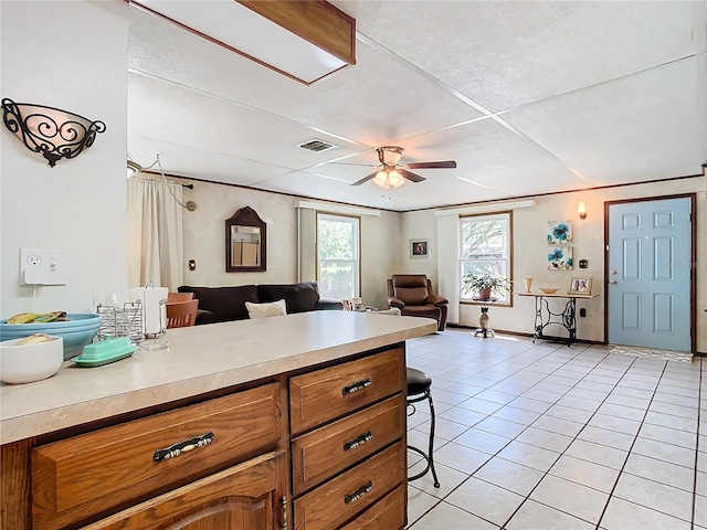 kitchen featuring ceiling fan, light tile patterned flooring, and a breakfast bar area